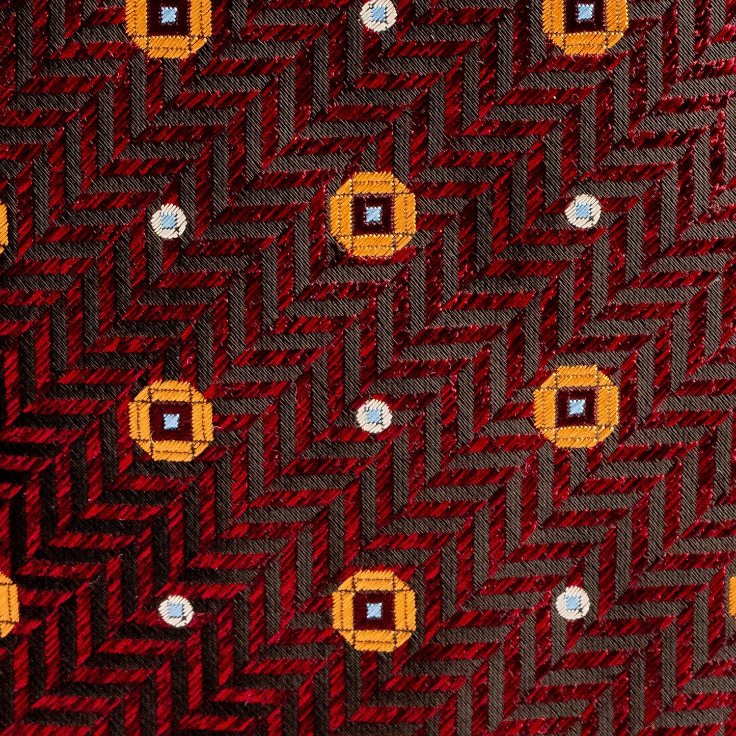 Patterned fabric with a red and black chevron design and yellow diamond shapes.