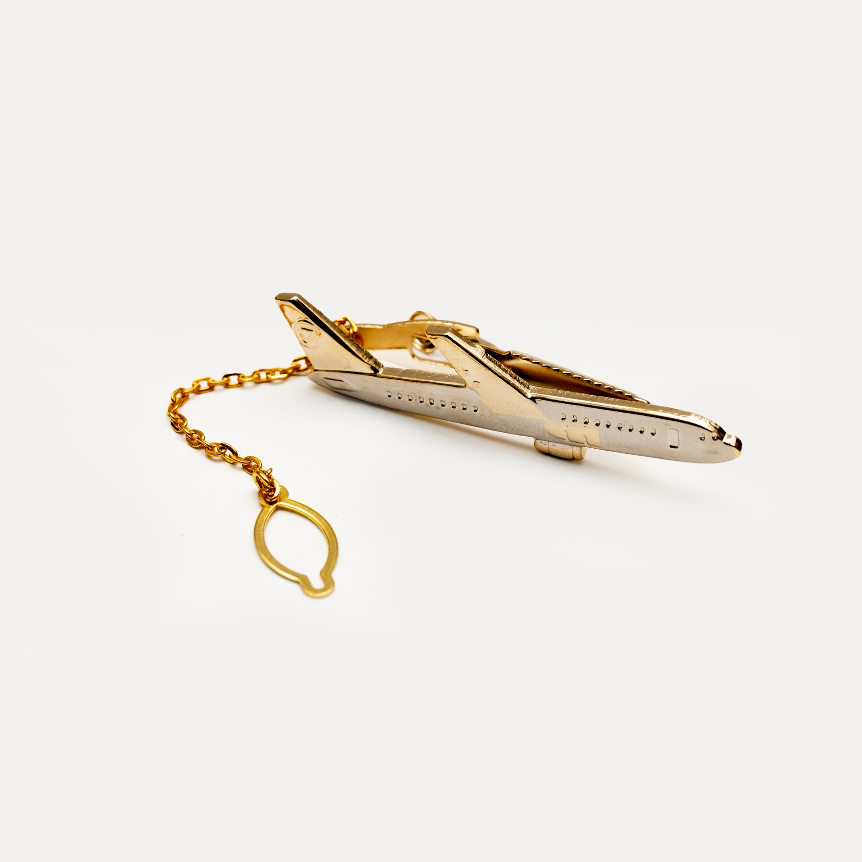 Gold airplane-shaped tie clip on a white background