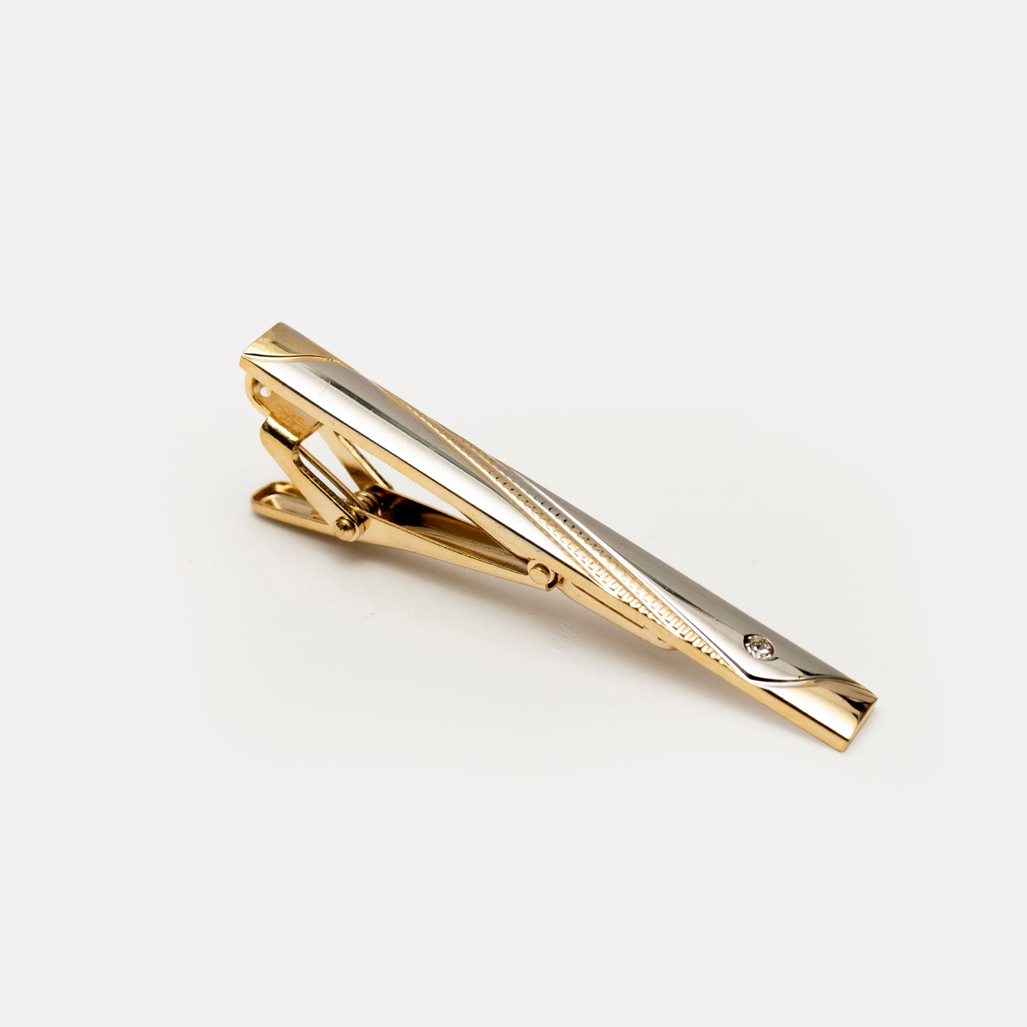 Gold tie clip on a light gray background