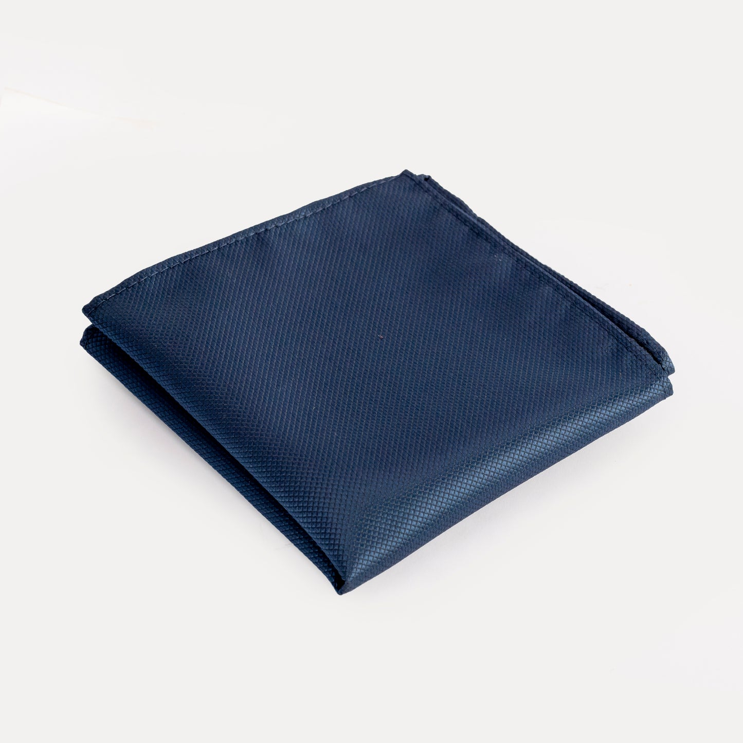 Folded navy blue pocket square on a light gray background