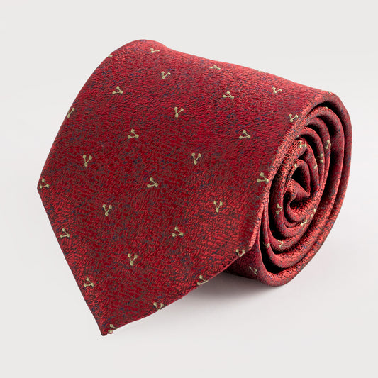 Rolled red tie with gold patterns on a light gray background