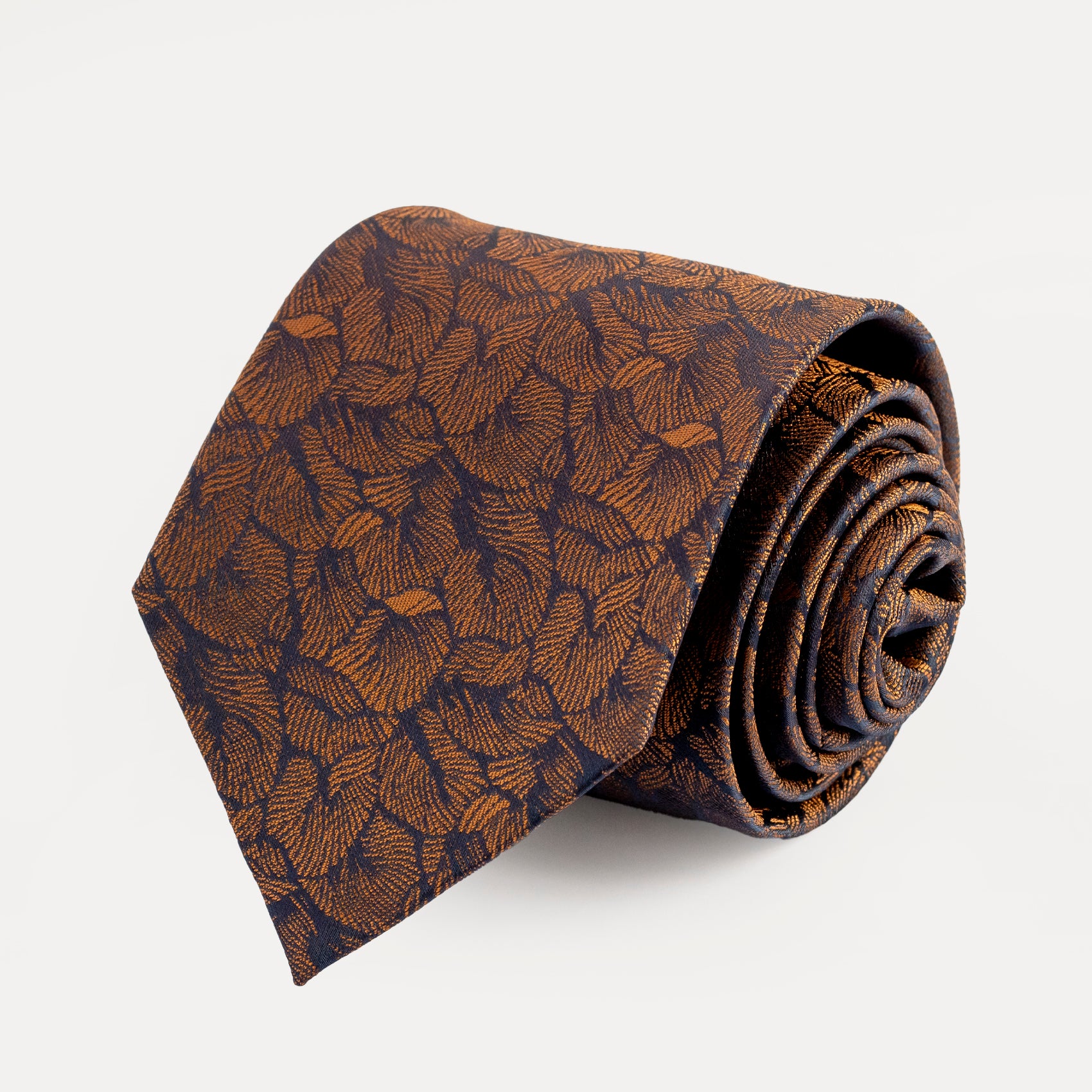 Rolled-up brown patterned tie on a light gray background