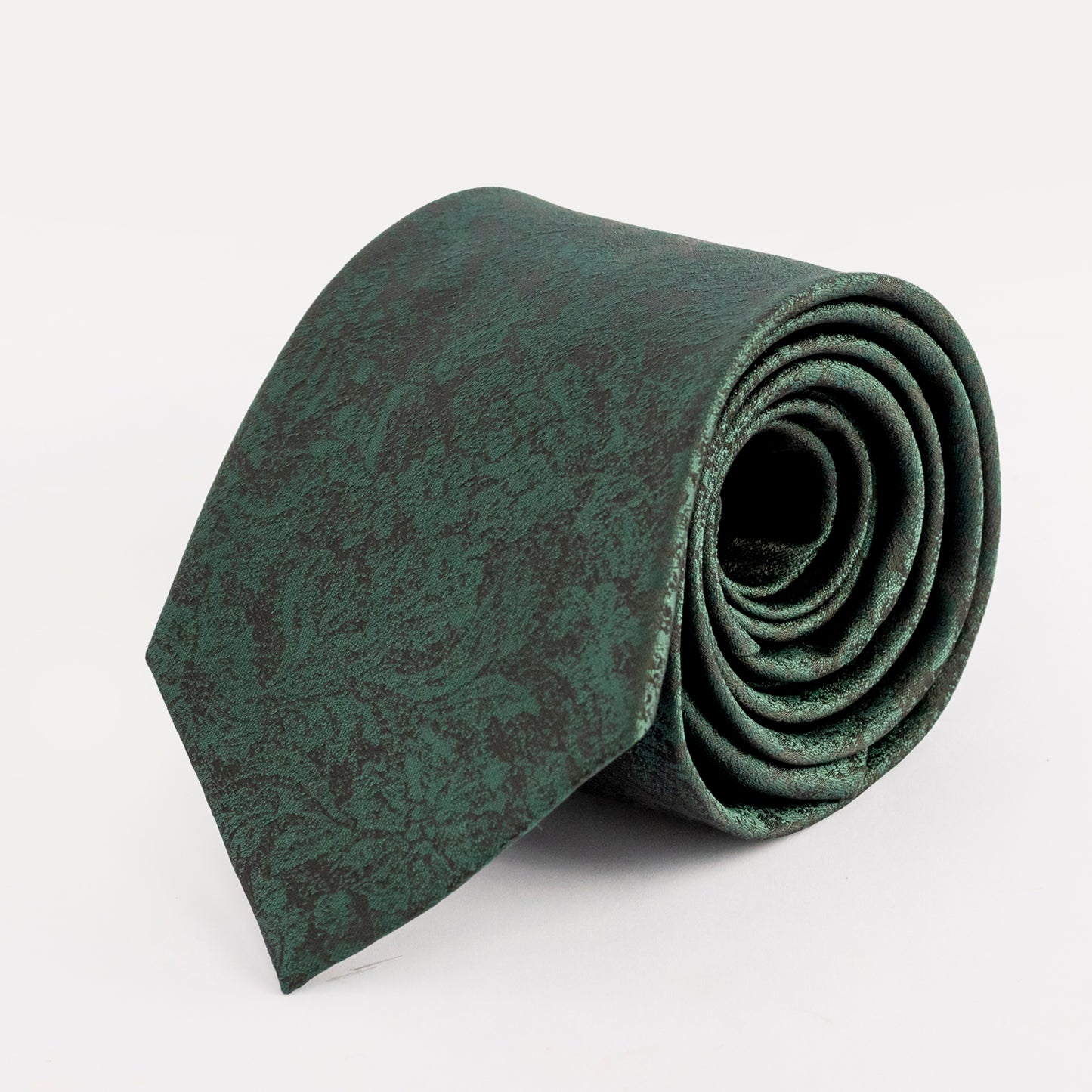 Rolled-up green patterned tie on a white background