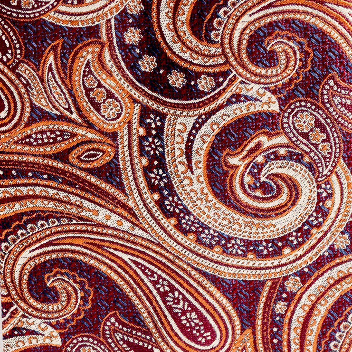 Close-up of a patterned fabric with swirls and paisley designs in brown, beige, and purple.