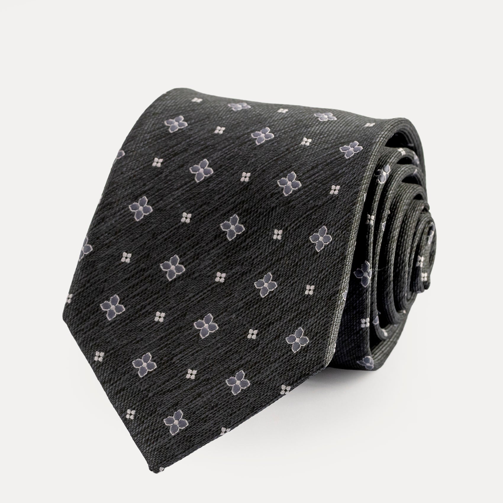 Roll of black tie with white floral pattern on a light gray background