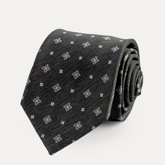 Roll of black tie with white floral pattern on a light gray background