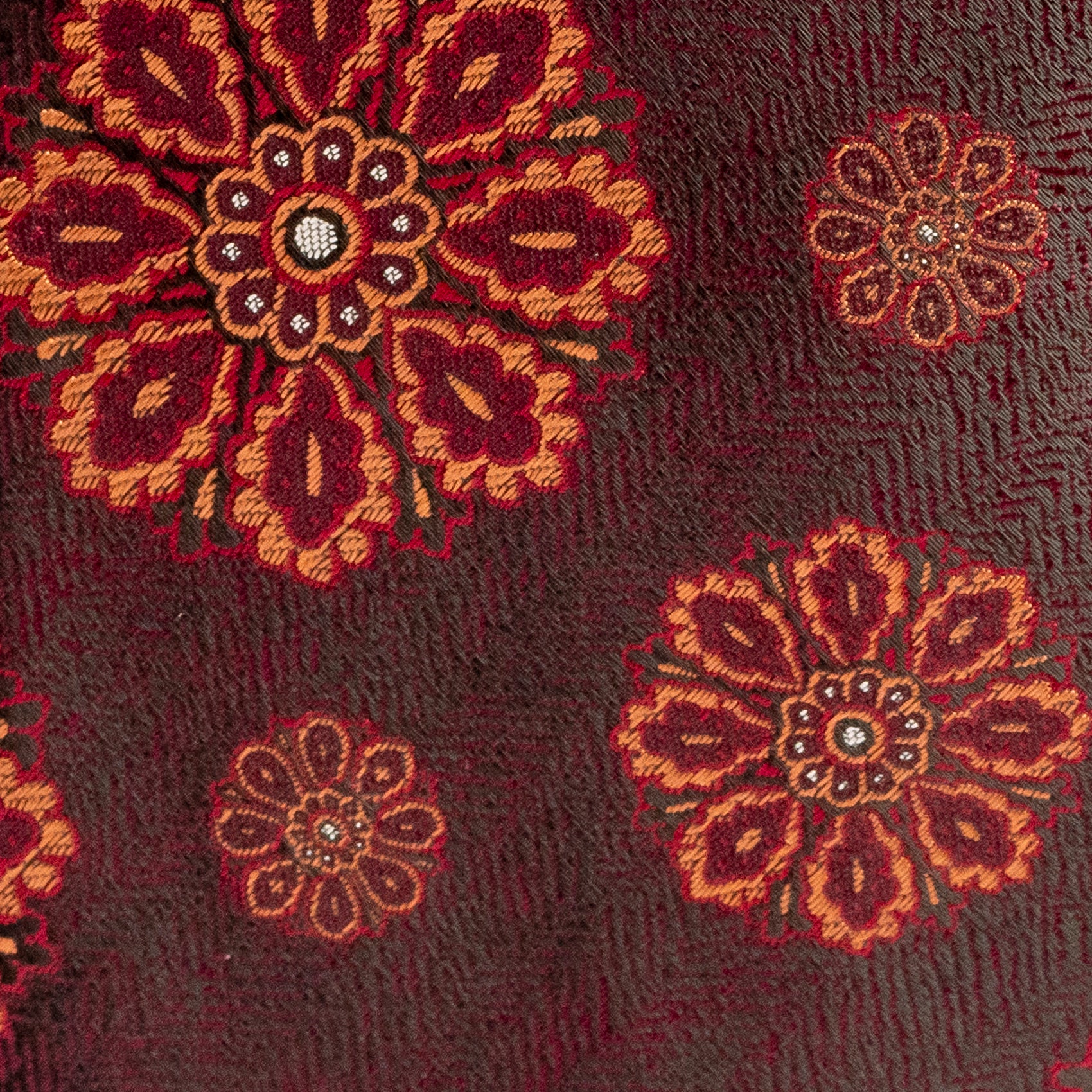 Close-up of a textured fabric with floral patterns in red and brown.