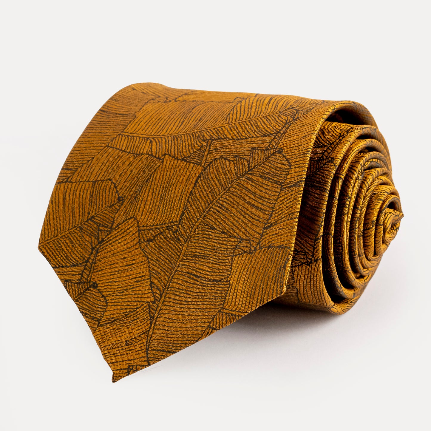 Rolled mustard yellow tie with leaf pattern on a white background