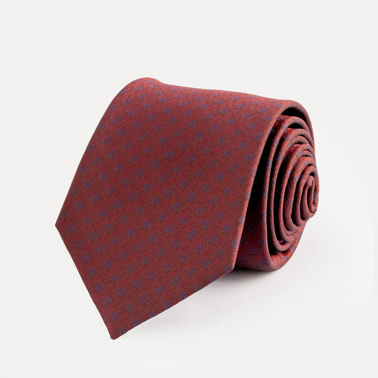 Folded burgundy tie with subtle pattern on a light gray background