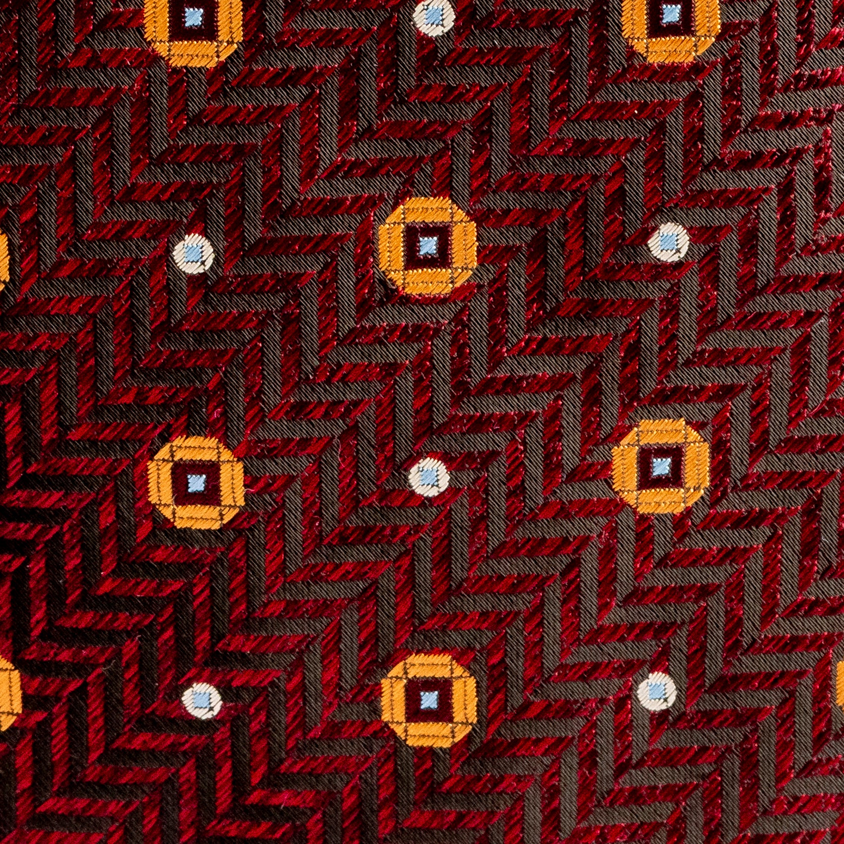 Patterned fabric with a red and black chevron design and yellow diamond shapes.
