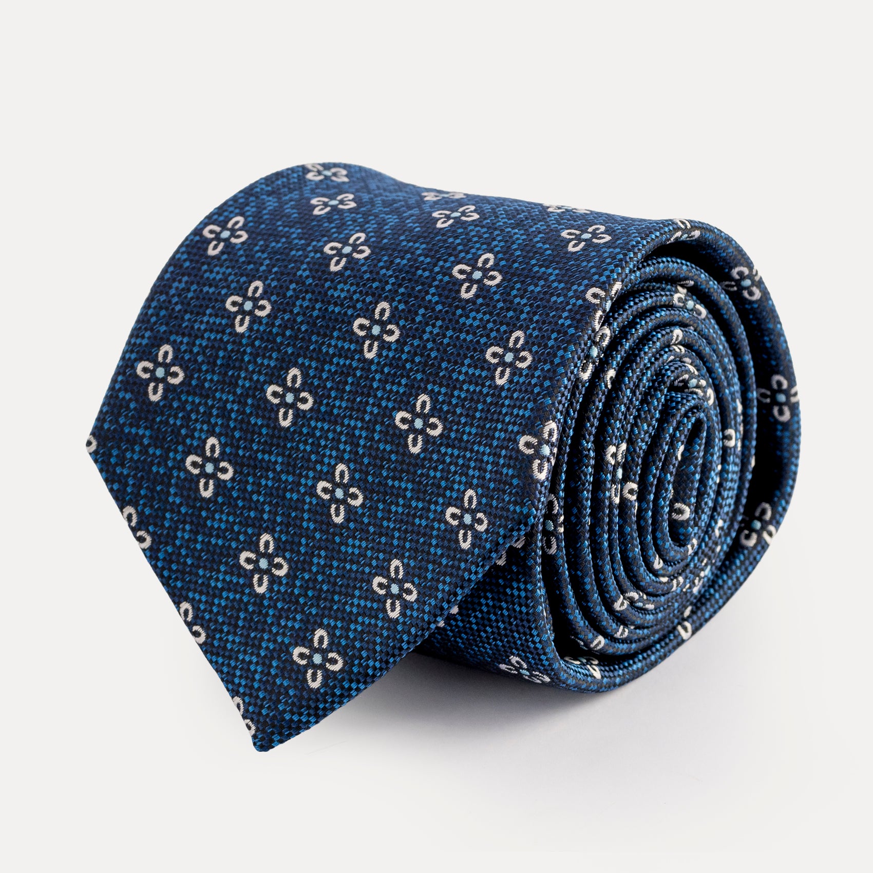 Rolled-up blue tie with floral pattern on a light gray background