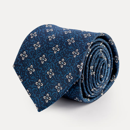Rolled-up blue tie with floral pattern on a light gray background