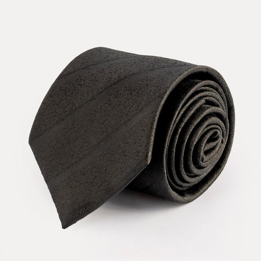 Rolled-up dark gray tie on a light gray background