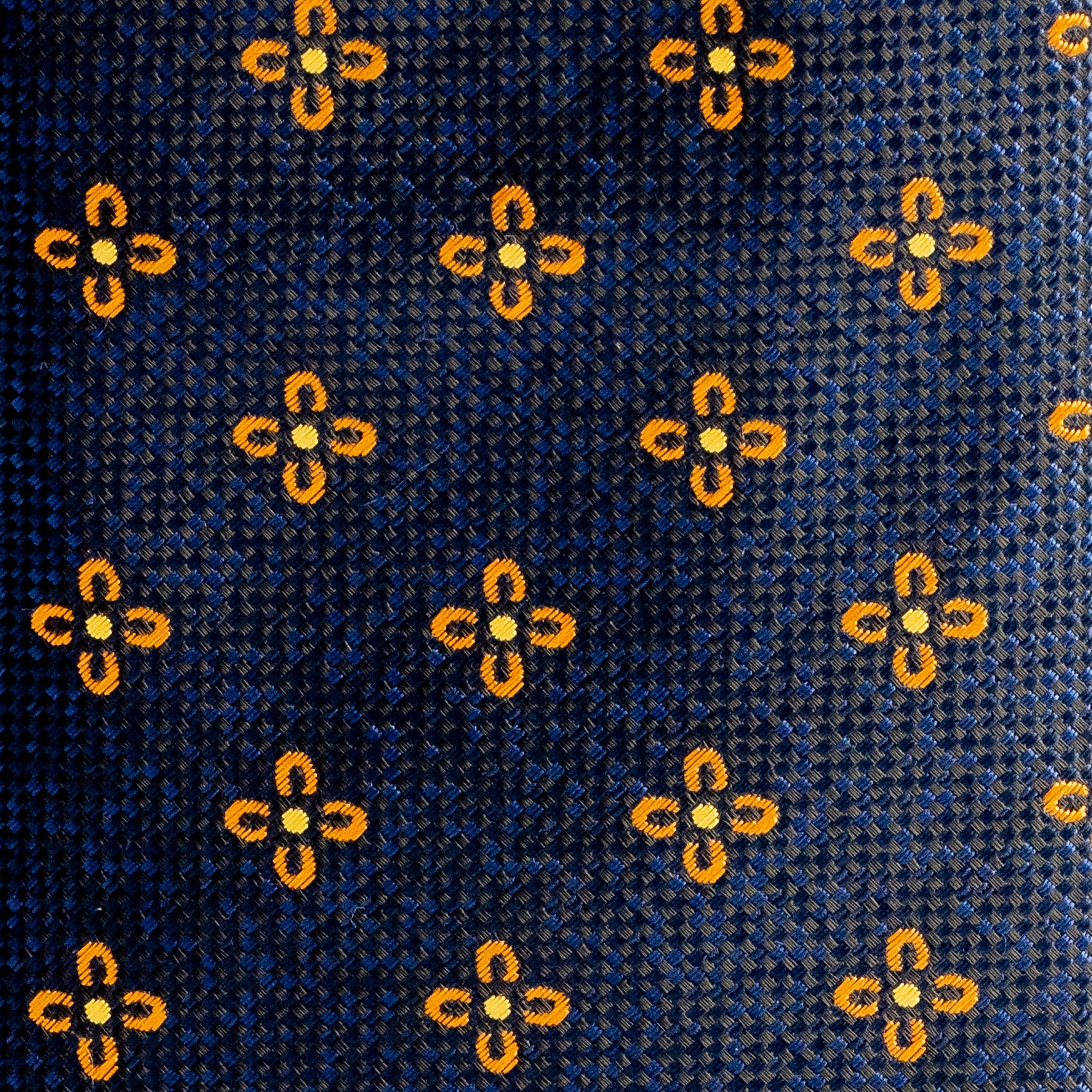 Close-up of a patterned fabric with yellow floral designs on a blue background