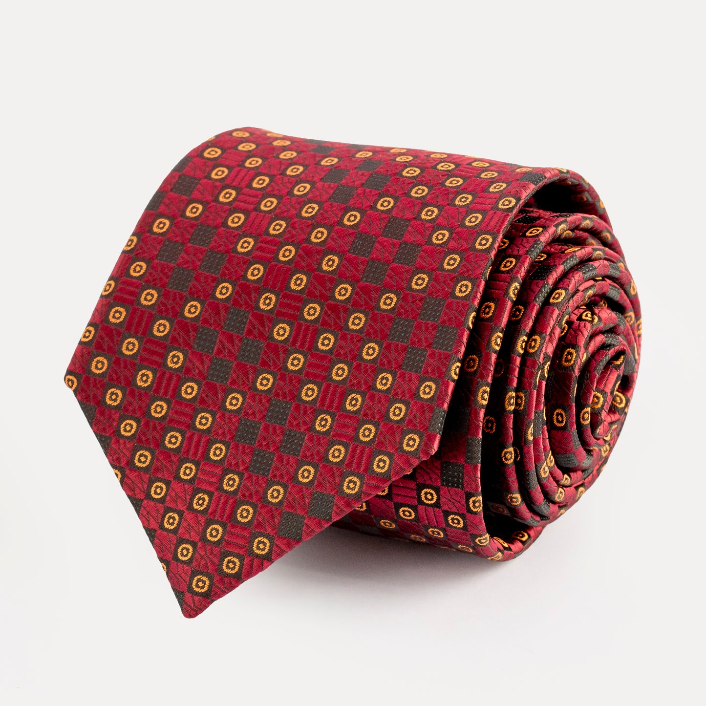 Folded red tie with gold and black pattern on a white background