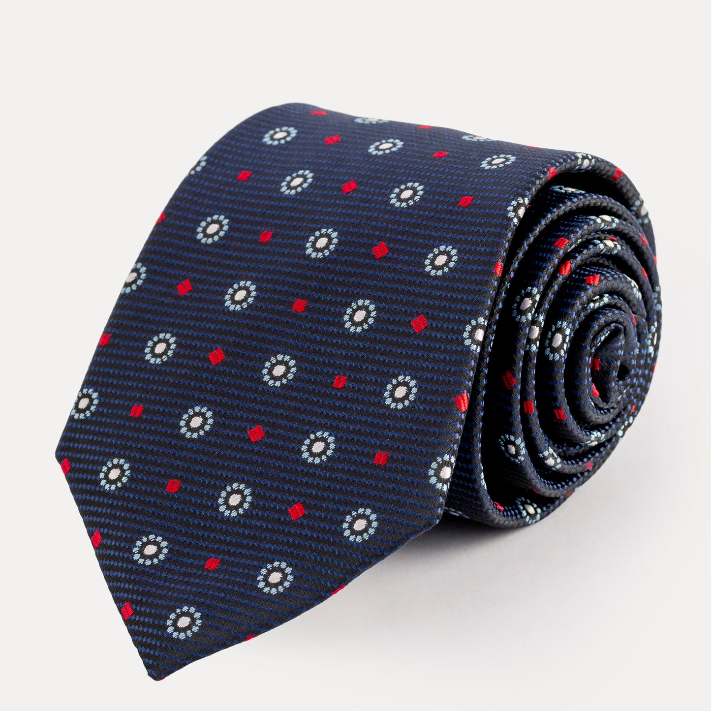 Roll of a navy blue tie with red and white pattern on a light gray background