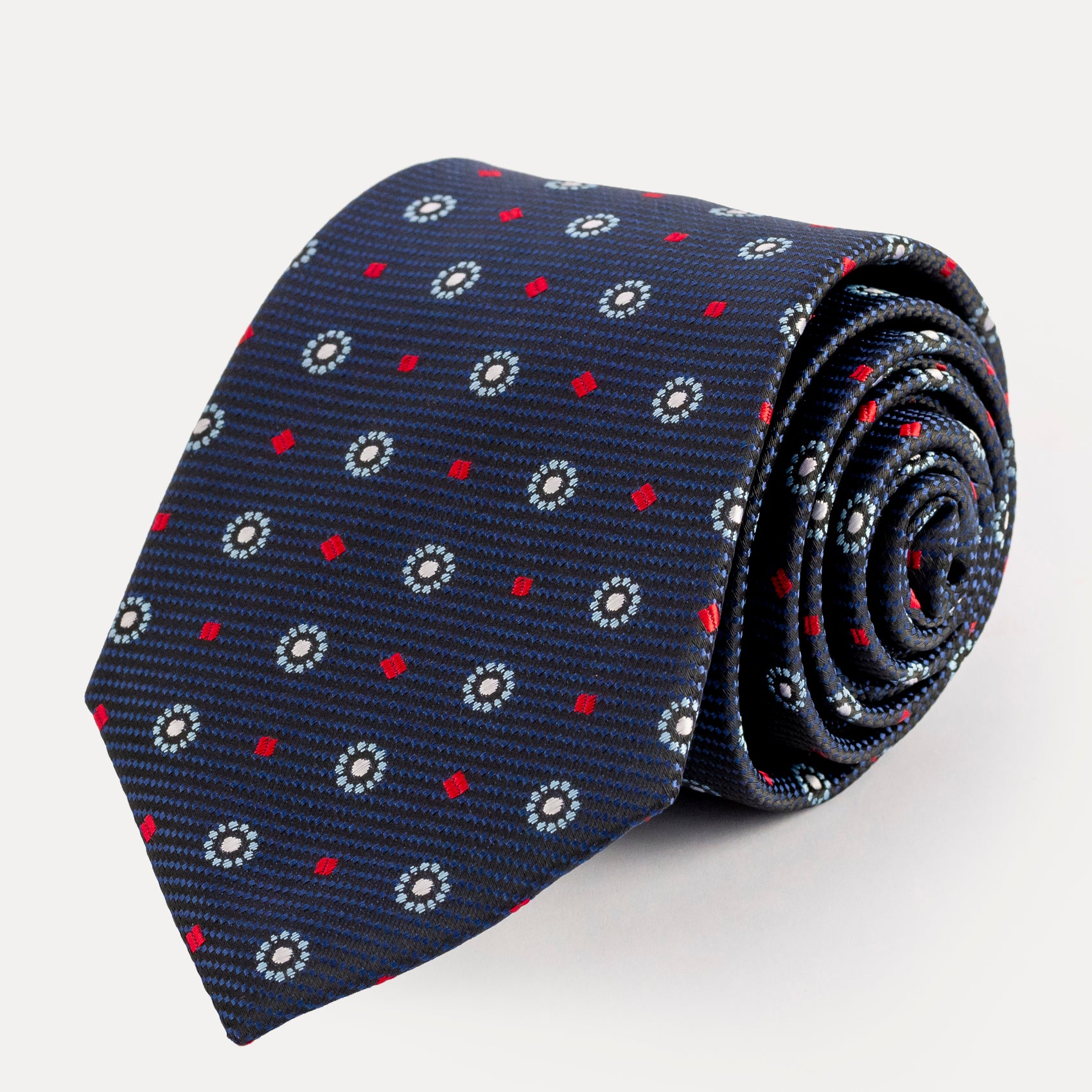Roll of a navy blue tie with red and white pattern on a light gray background