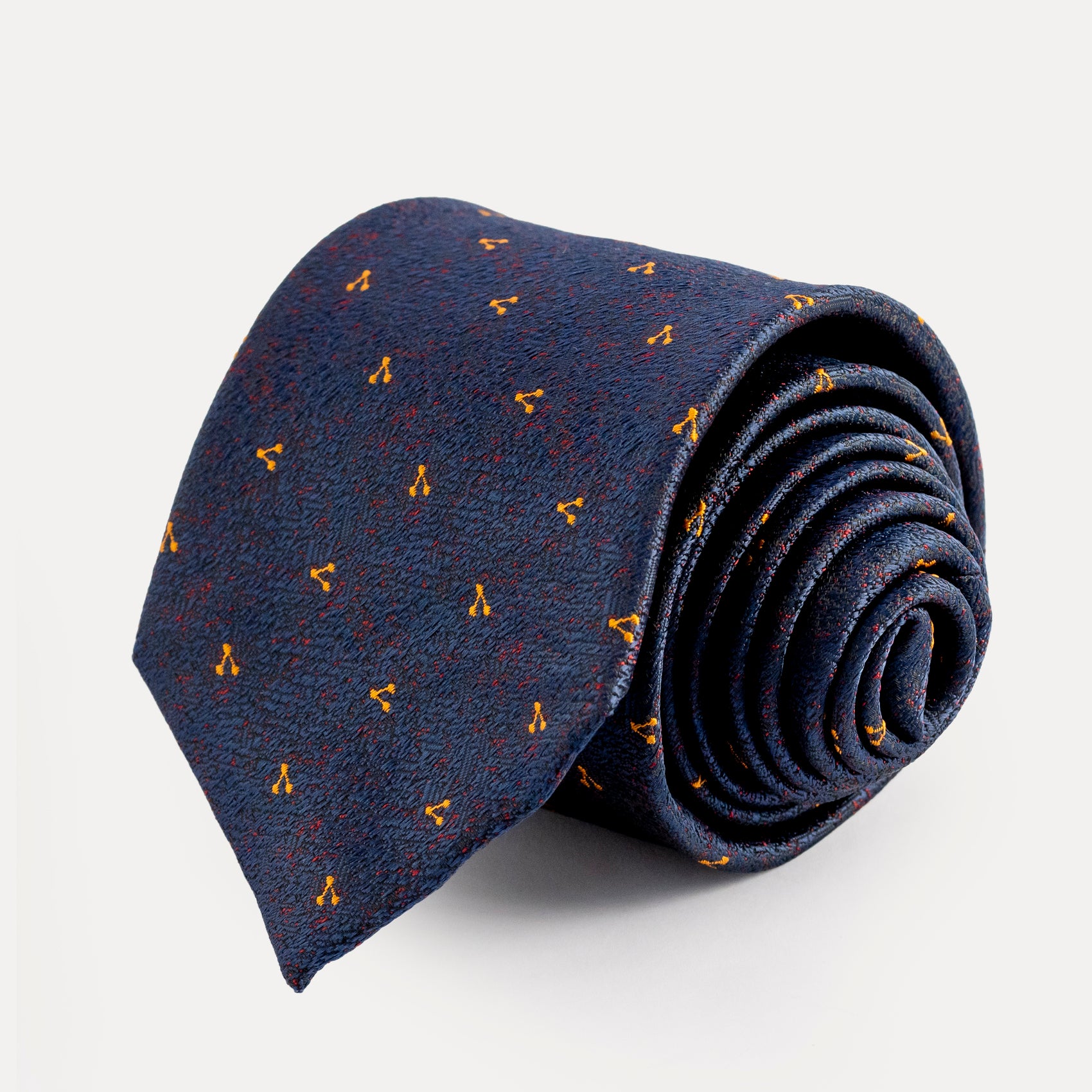 Rolled-up navy blue tie with small yellow patterns on a light gray background