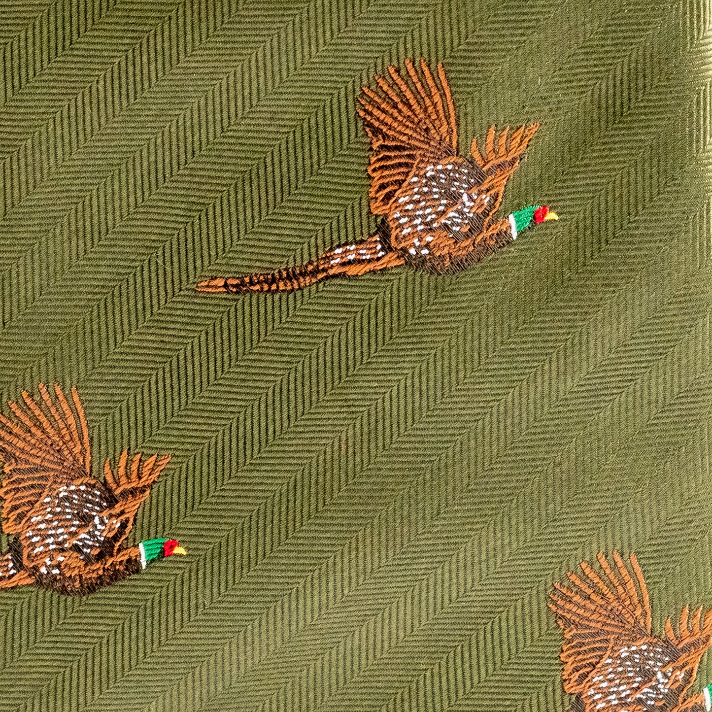 Embroidered pheasant design on a green fabric background