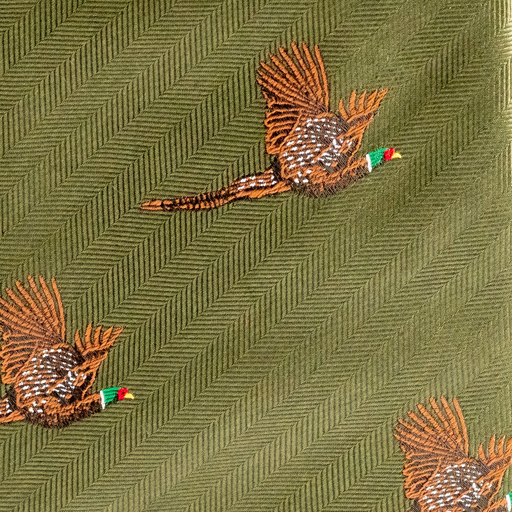 Embroidered pheasant design on a green fabric background