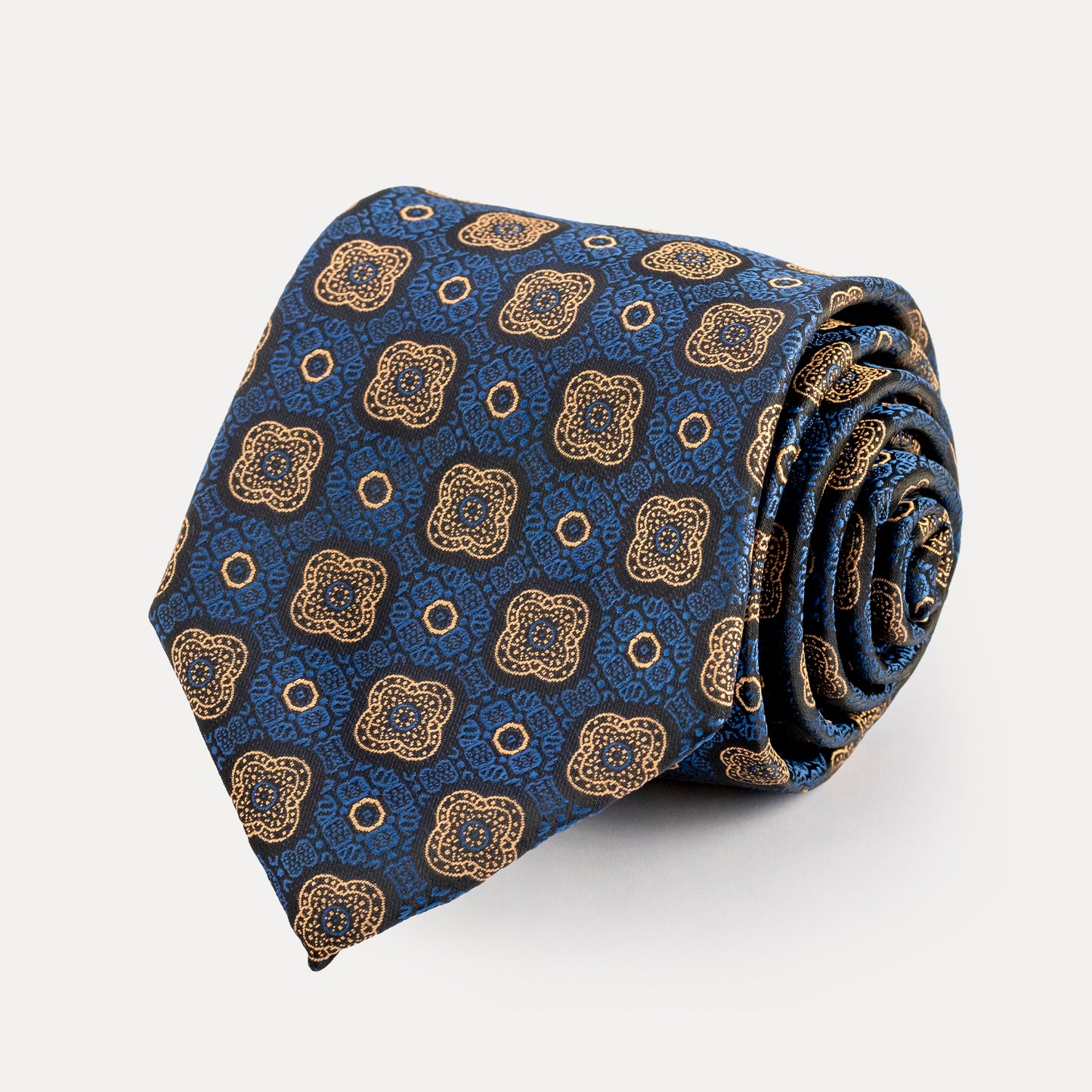 Rolled-up blue tie with gold geometric pattern on a white background