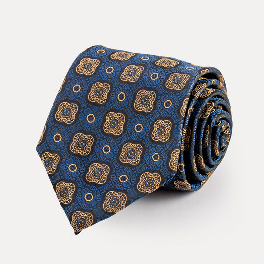 Rolled-up blue tie with gold geometric pattern on a white background